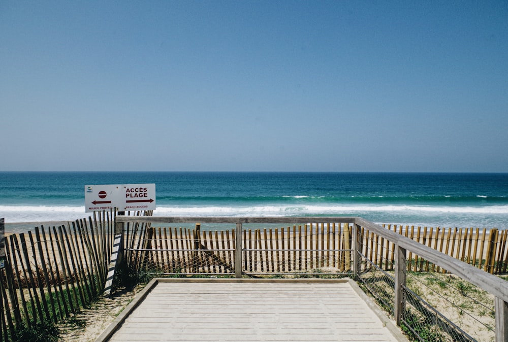 a wooden walkway leading to the beach with a sign on it