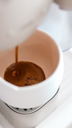 Steaming coffee pouring into a glass cup on a bright morning