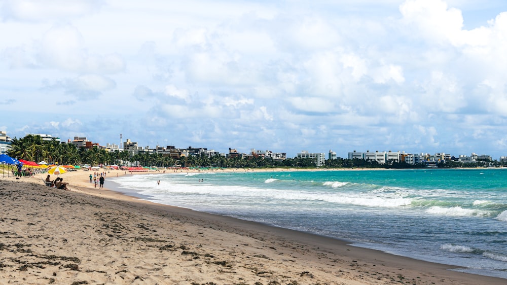 a beach with people walking on it and buildings in the background