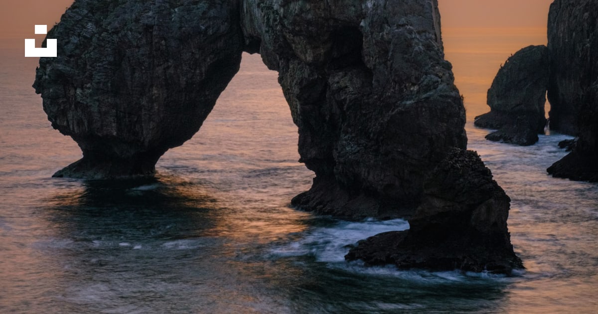 A large rock formation in the middle of the ocean photo – Free ...