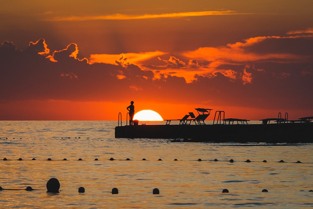 a man standing on a boat in the ocean at sunset