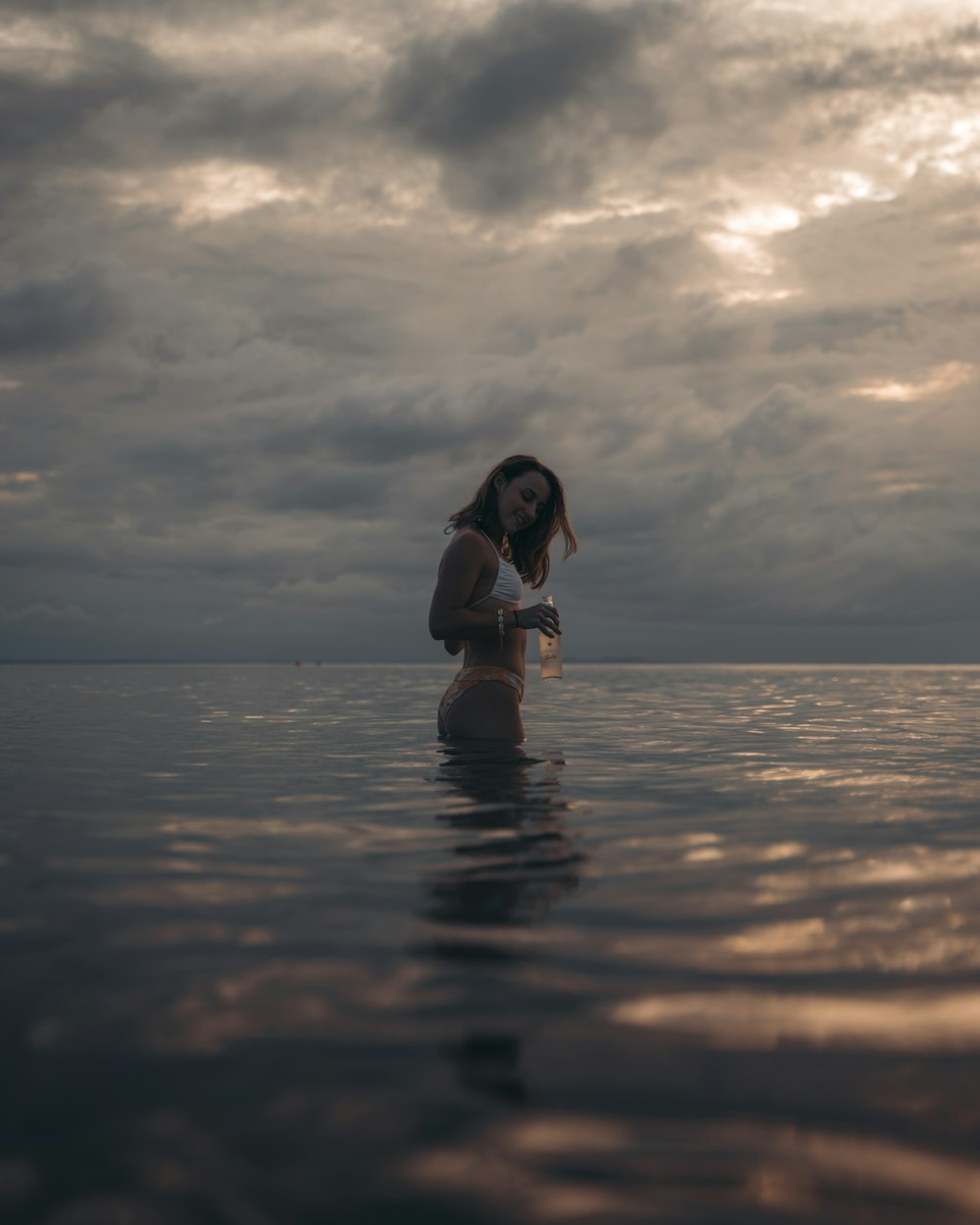 a woman standing in the water with her head in her hands