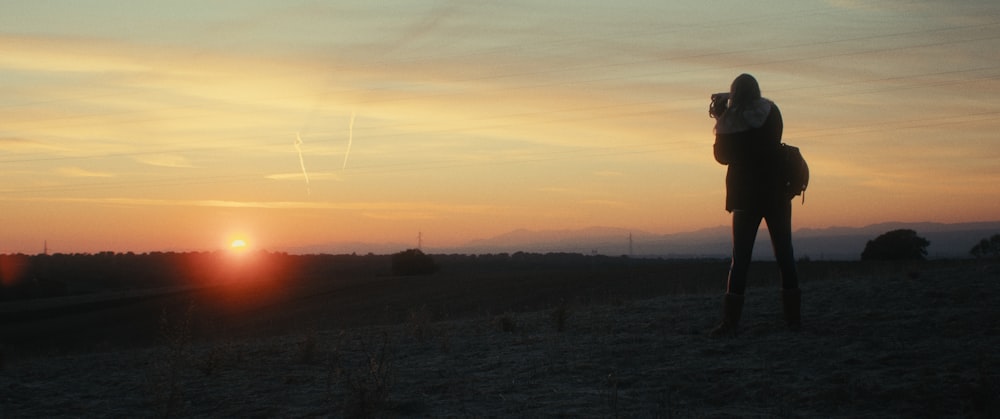 Eine Person, die bei Sonnenuntergang auf einem Feld steht