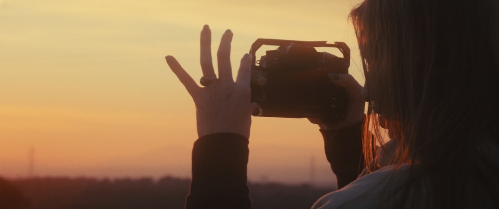 a woman taking a picture of a sunset with her camera