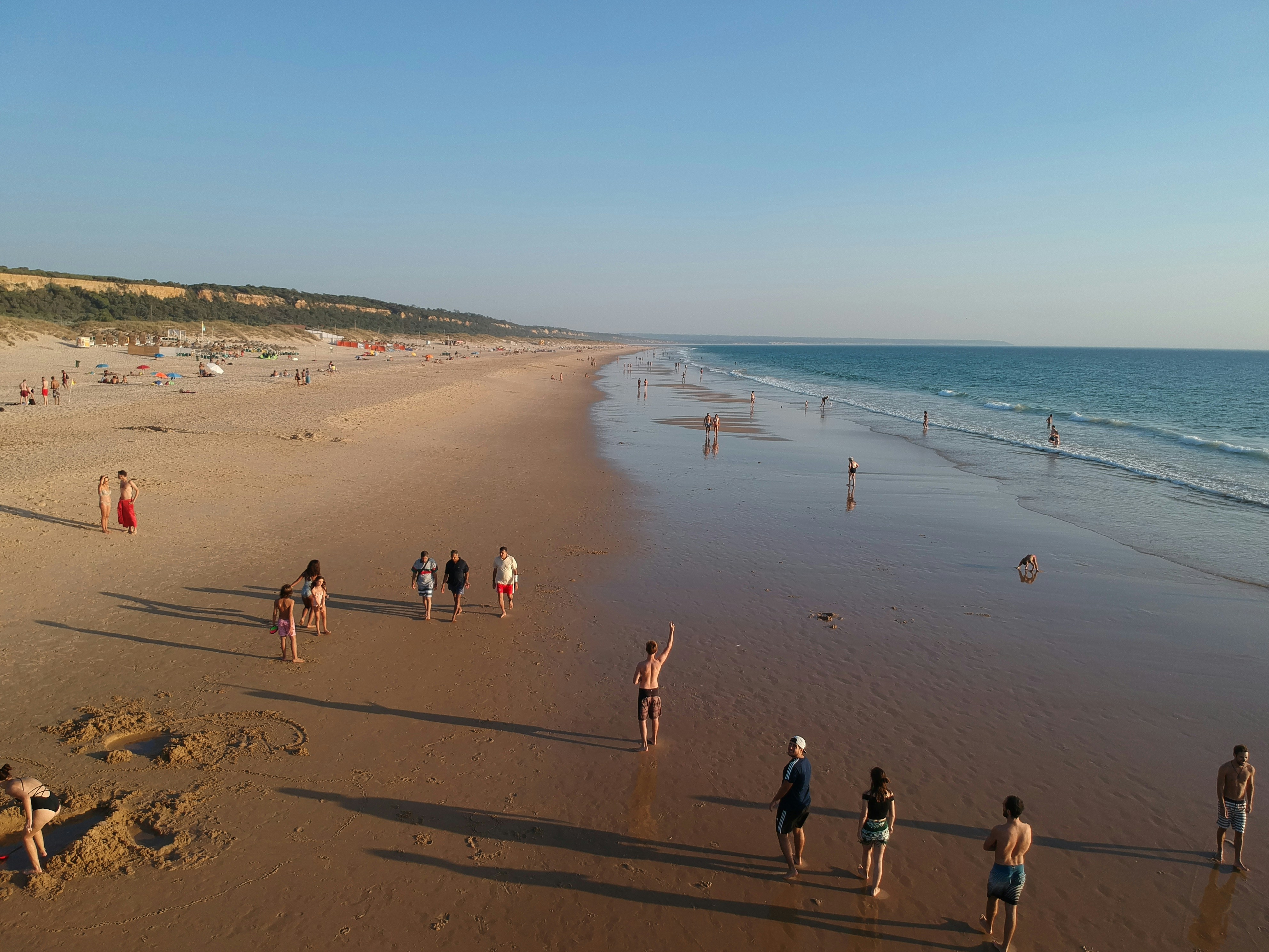 a group of people standing on top of a sandy beach