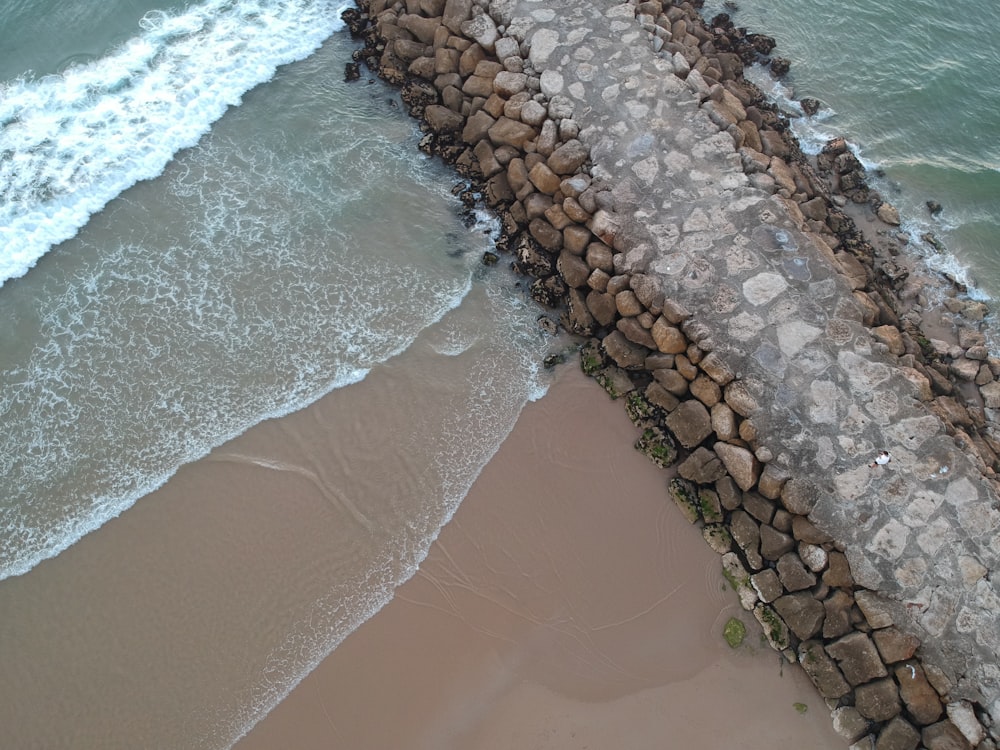 a stone wall next to the ocean with waves coming in