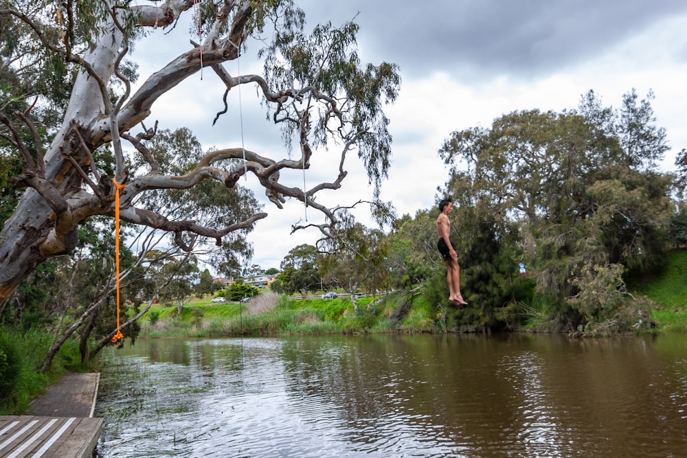 Eine Person, die an einem Baum über einem Gewässer hängt