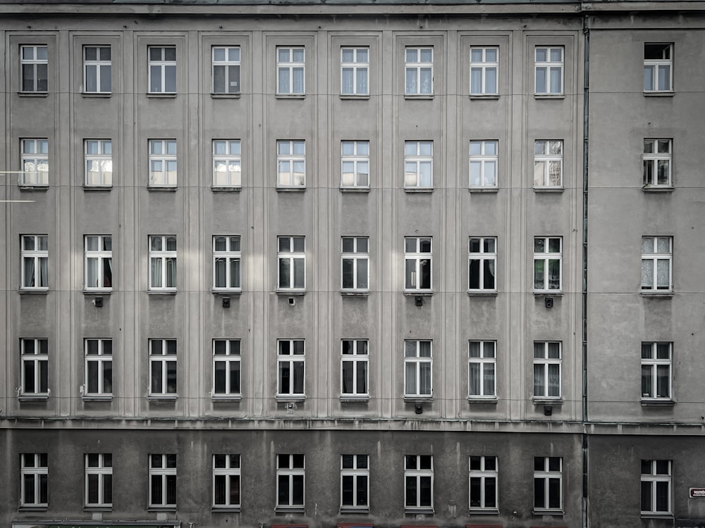 a tall building with many windows and a red car parked in front of it