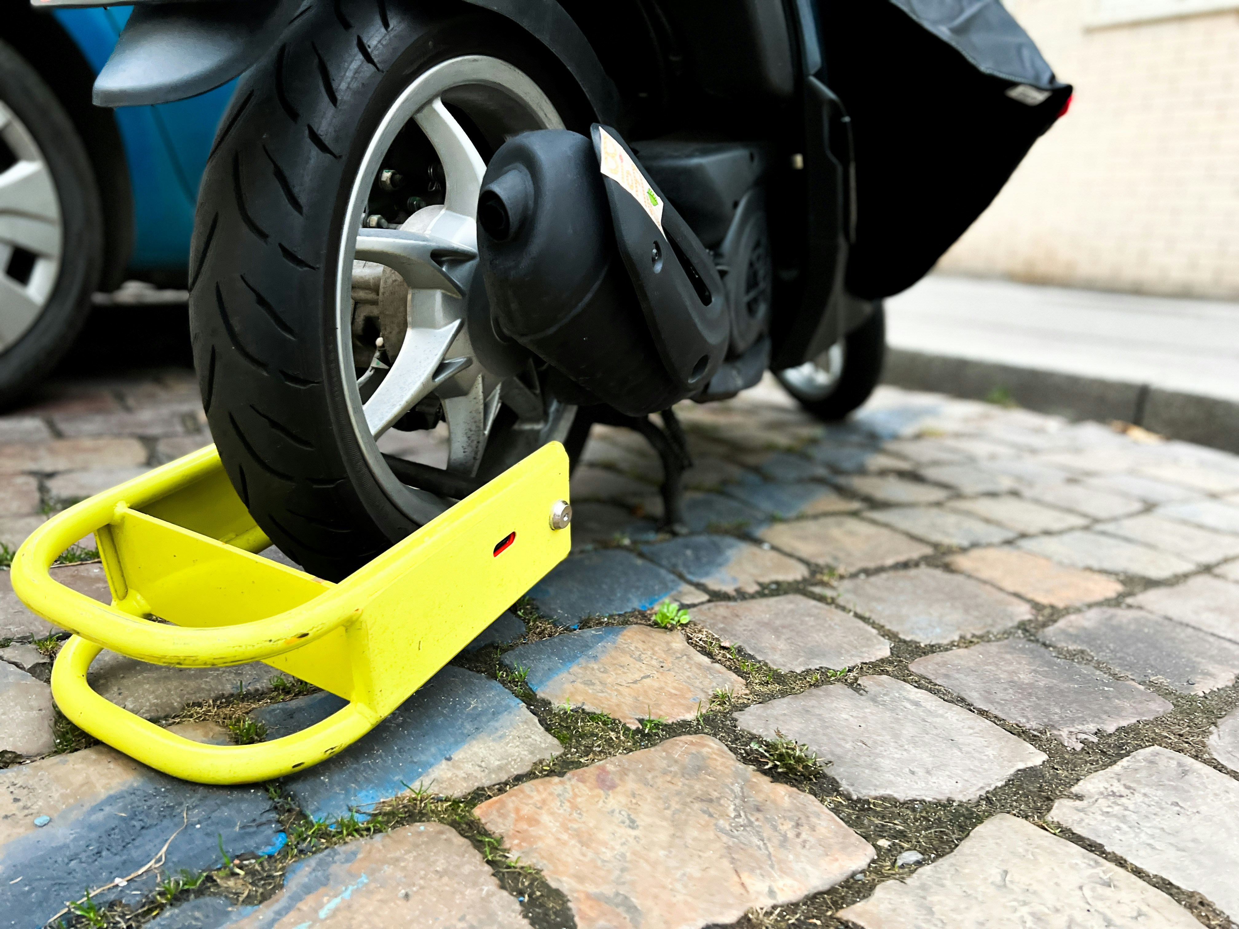 A scooter is parked on a cobblestone street photo Free Wheel lock Image on Unsplash