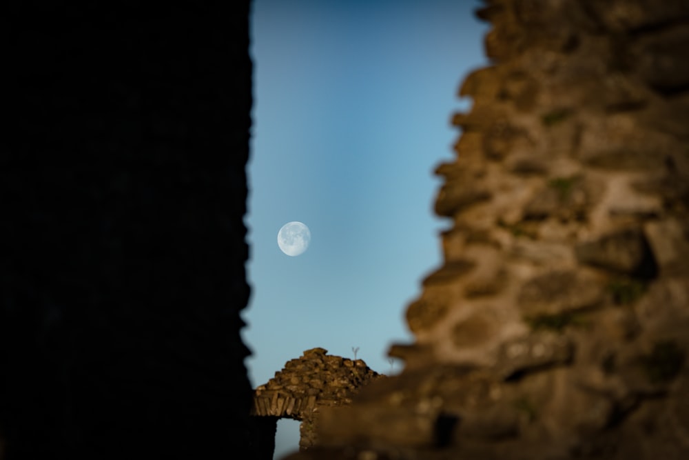 a view of the moon through a stone wall