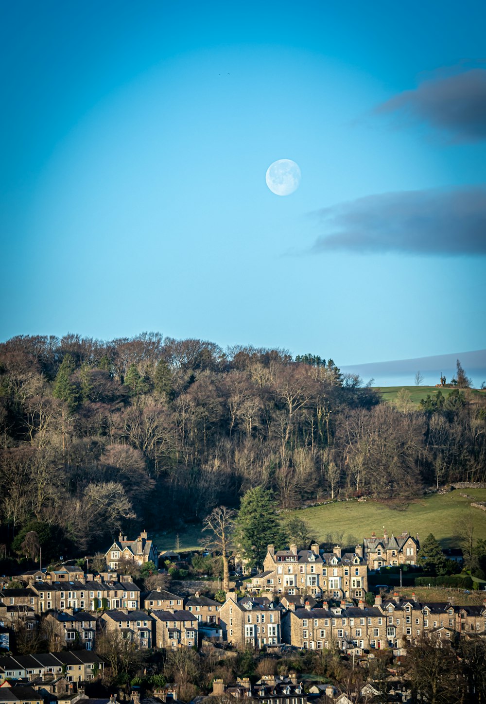 a full moon is seen over a small town