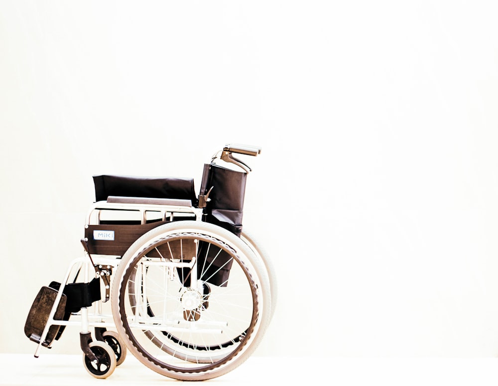Un fauteuil roulant à roulettes est représenté sur un fond blanc