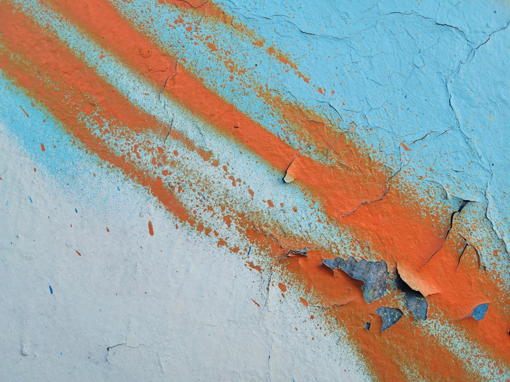 a blue and orange wall with peeling paint