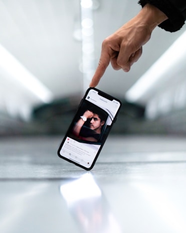 a hand holding a cell phone with a picture of a man on it