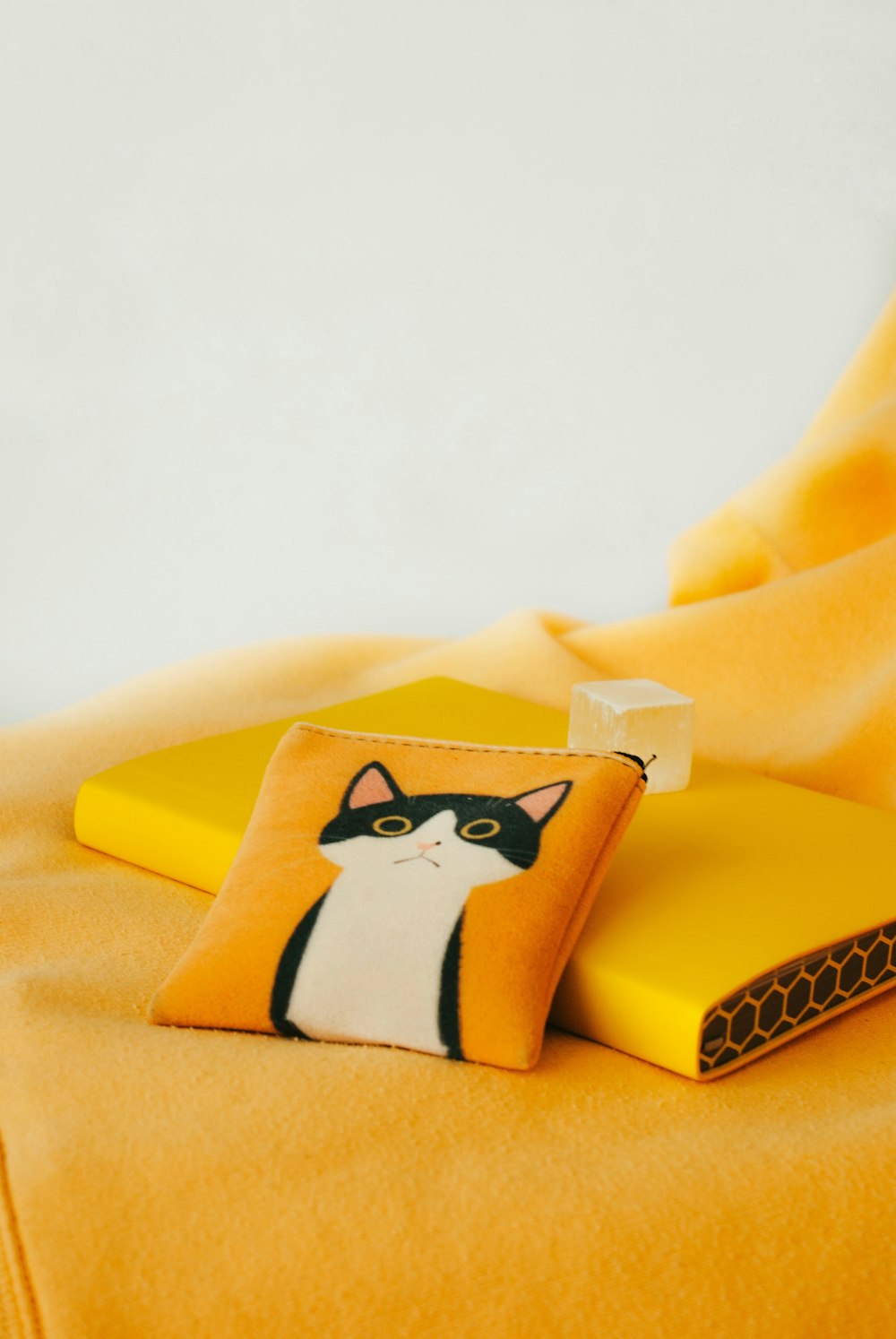 a cat pillow sitting on top of a yellow blanket