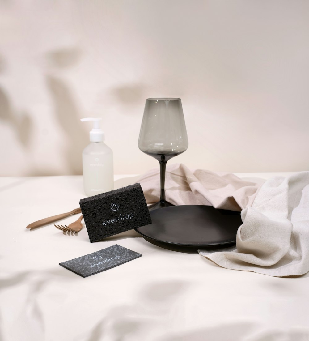 a table topped with a black plate and a bottle of lotion