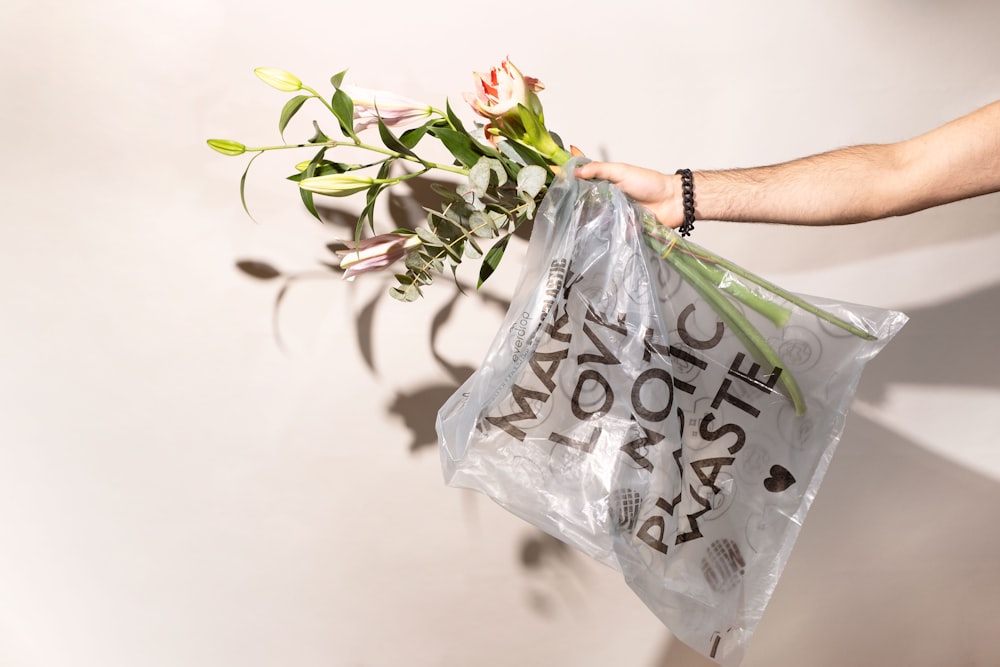 a person holding a plastic bag with flowers in it