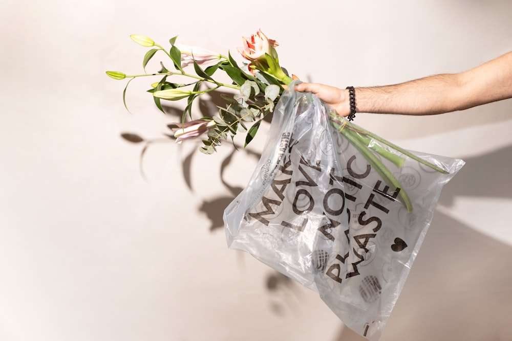 una persona sosteniendo una bolsa de plástico con flores en ella