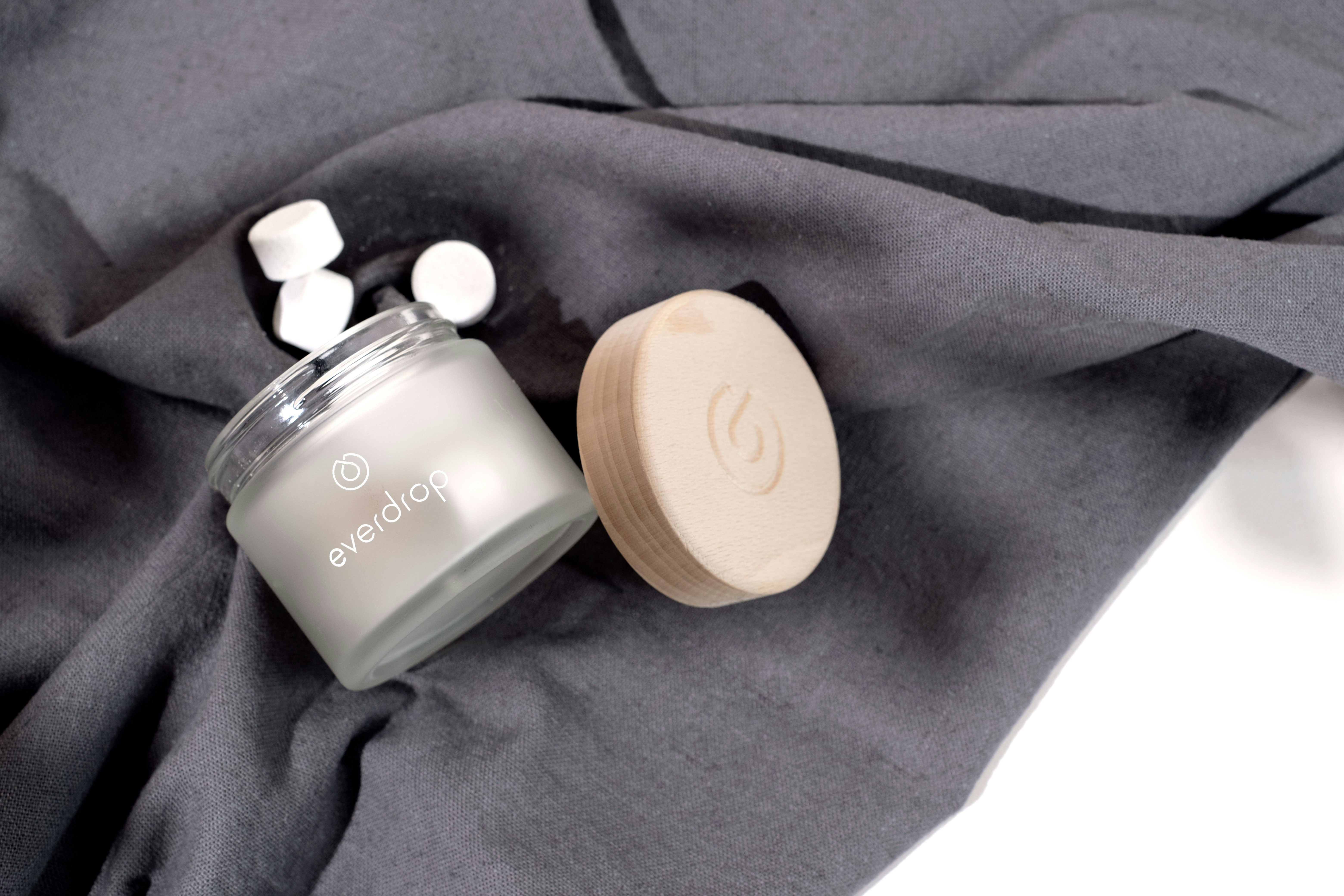 a jar of cream sitting on top of a gray blanket