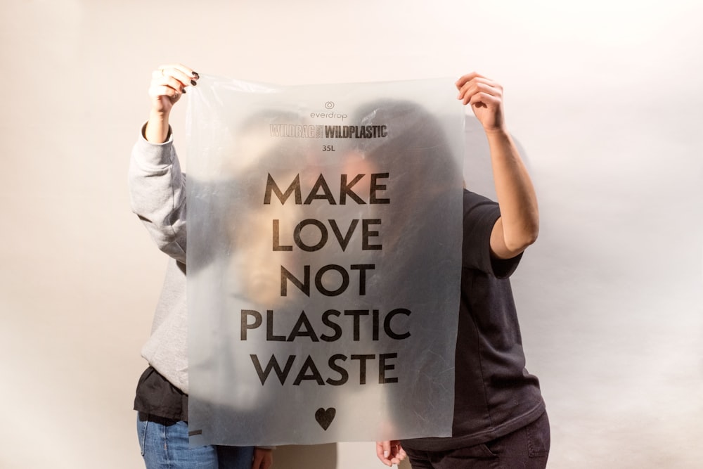 Dos personas sosteniendo un cartel que dice Make Love, Not Plastic Waste