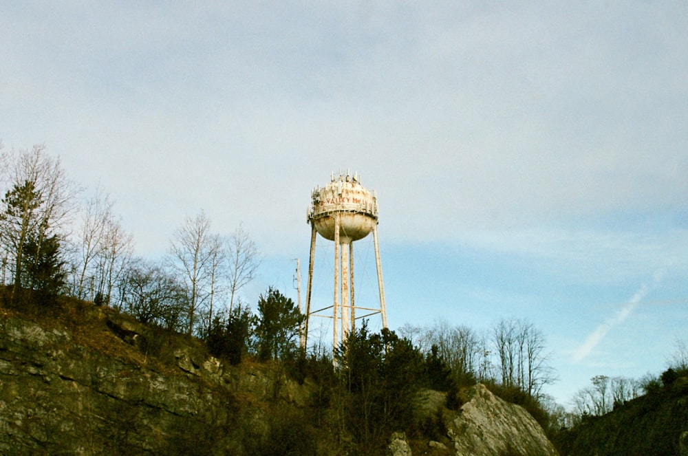 a tall water tower sitting on top of a lush green hillside