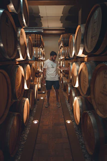 a man standing in a room full of wine barrels