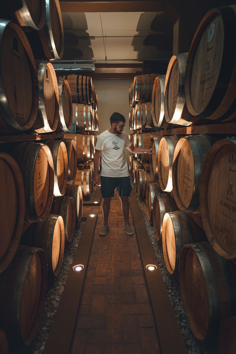 a man standing in a room full of wine barrels