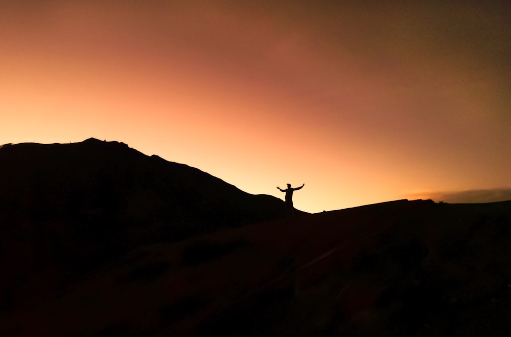 a person standing on top of a hill at sunset