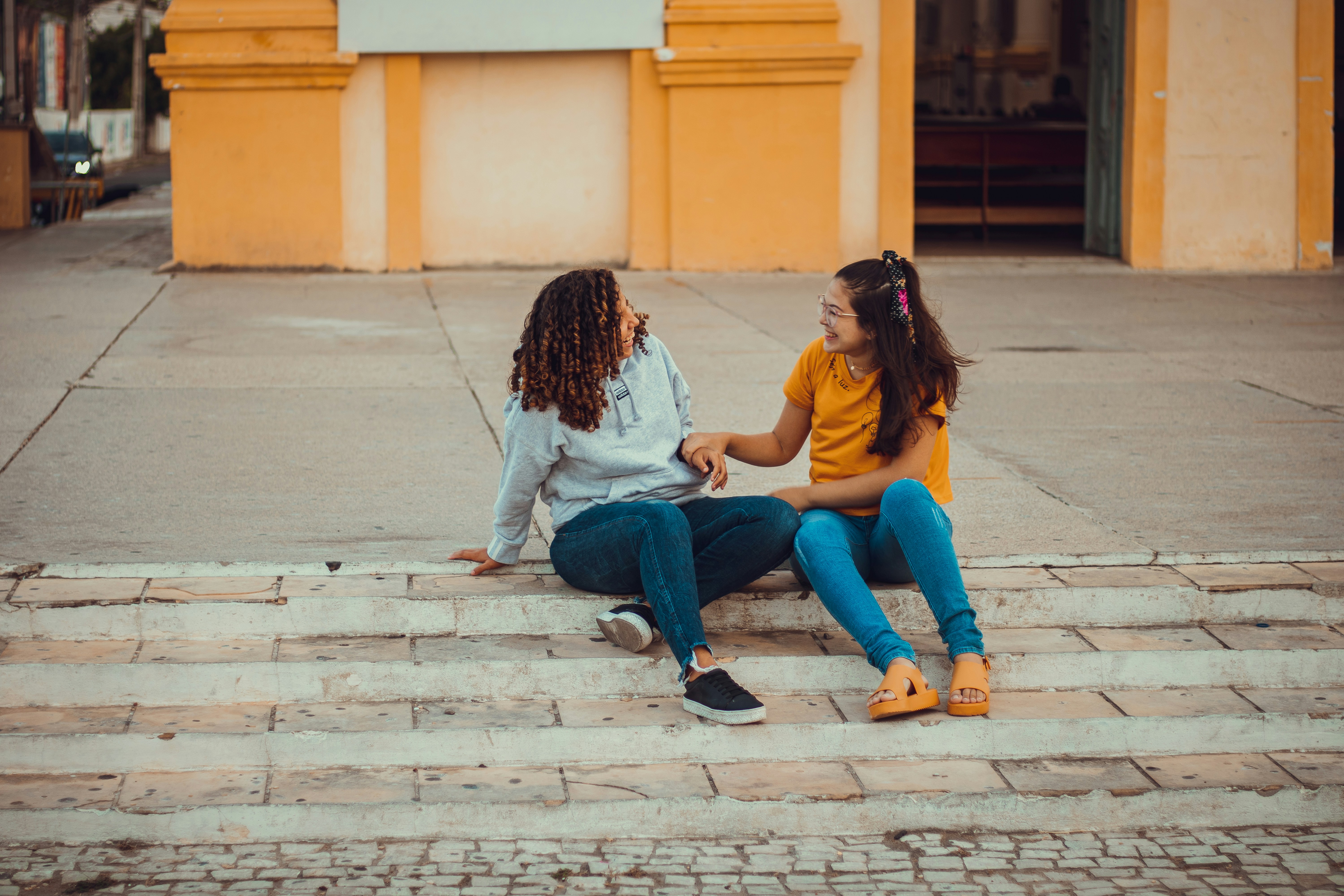 two girls sitting on the steps of a building
