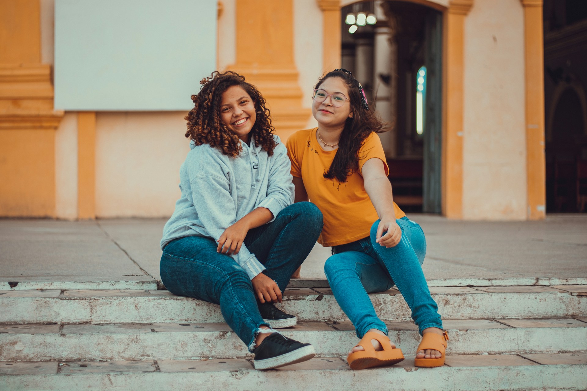 two women sitting on the steps of a building