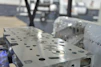 Close-up of a satisfied customer holding a laser-cut machine part with a bright workshop background.