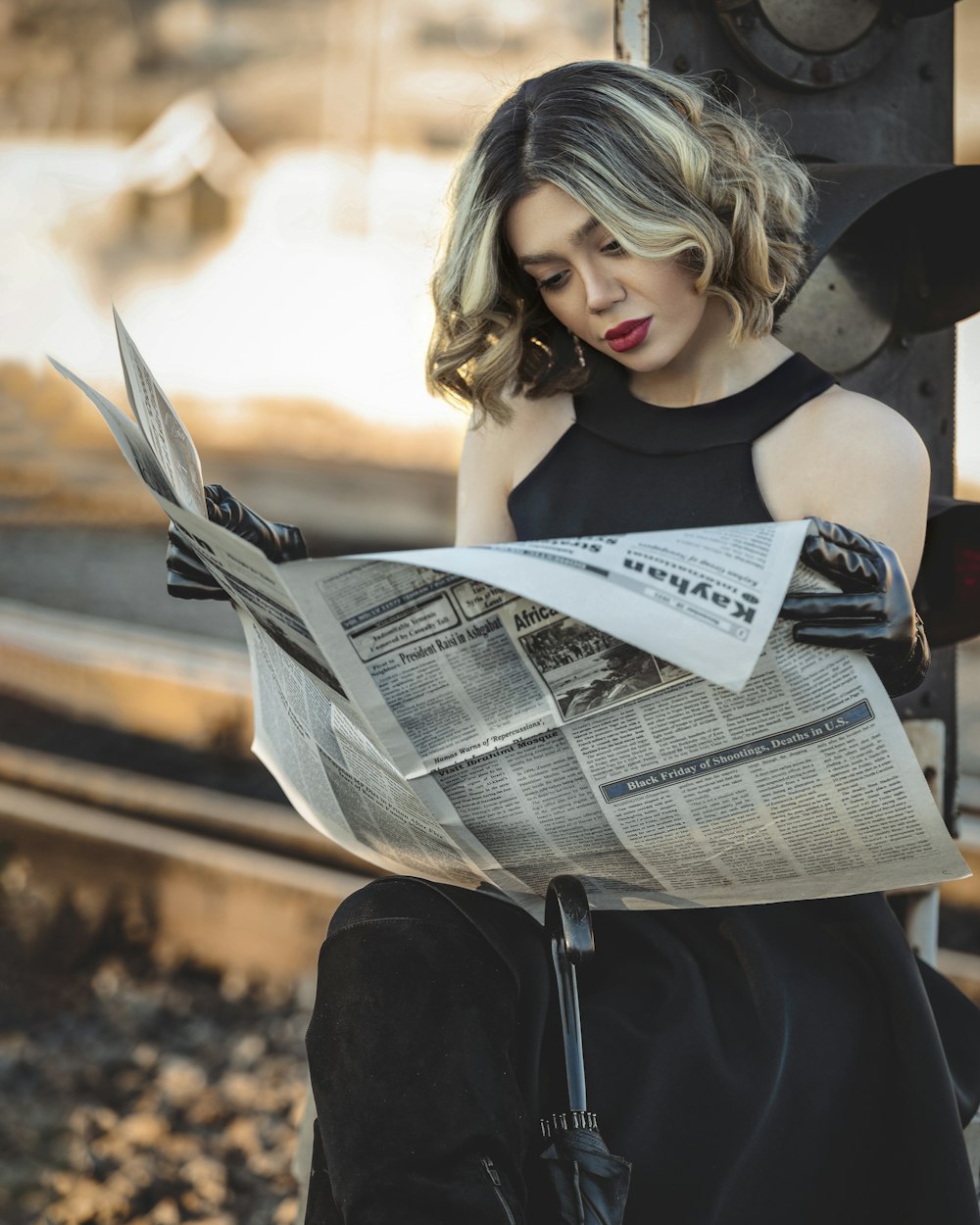 a woman in a black dress is reading a newspaper
