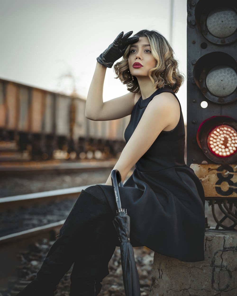 a woman in a black dress sitting on a train track