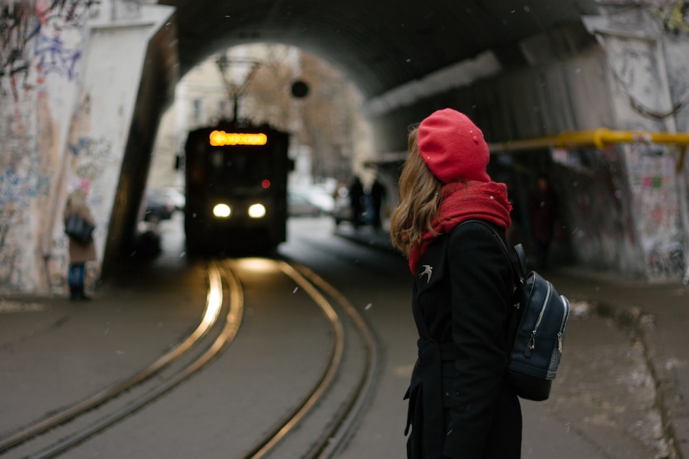 a woman in a red hat is standing in a tunnel