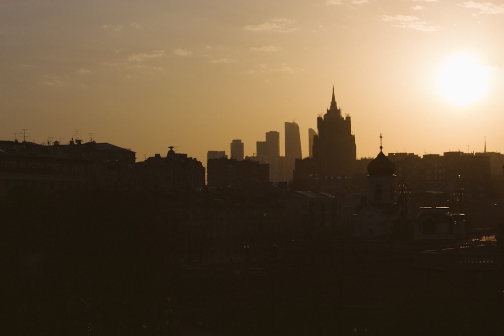 the sun is setting over a city with tall buildings