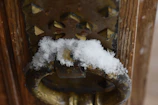Close-up of a sleek dimansi video doorbell mounted on a modern black front door with soft snowfall in the background