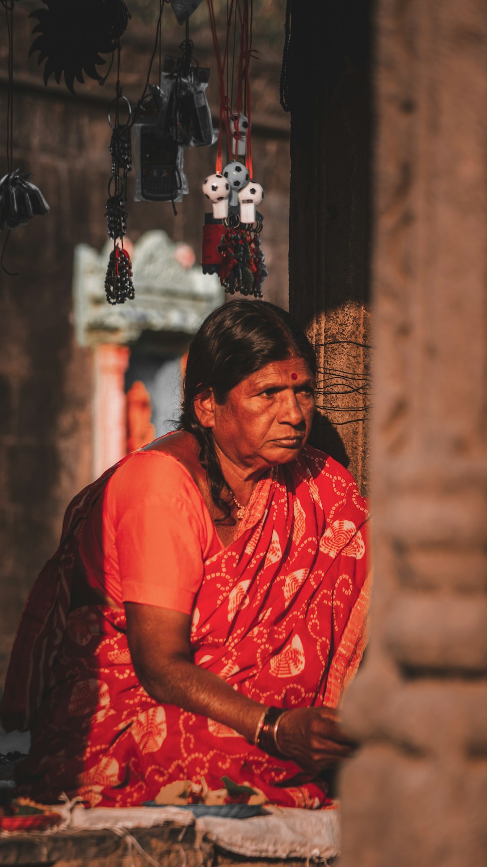 a woman in a red sari sitting on a ledge