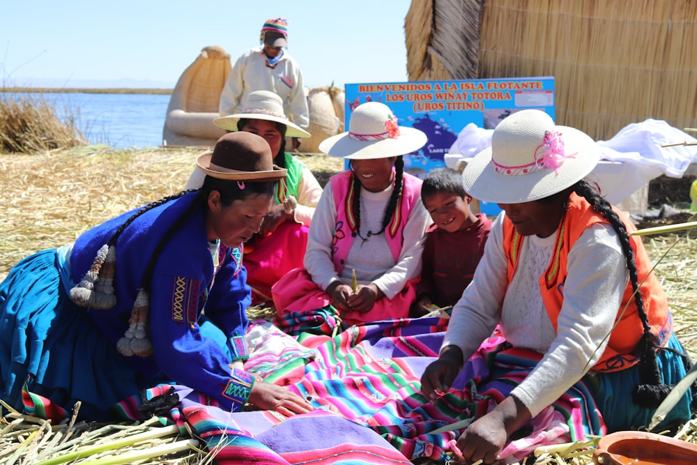 a group of women sitting on top of a grass covered field