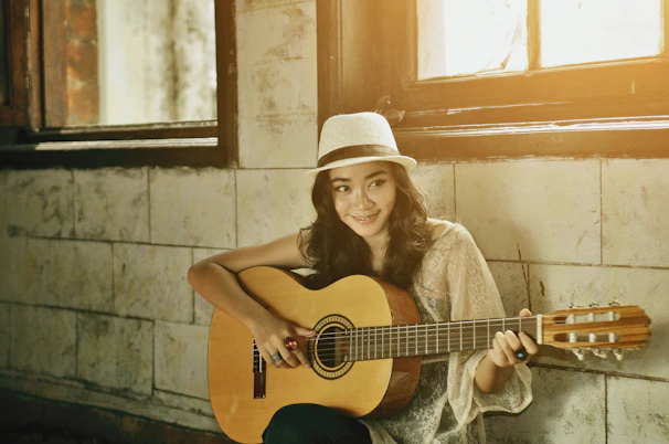 a woman with a hat is holding a guitar and online guitar tuner