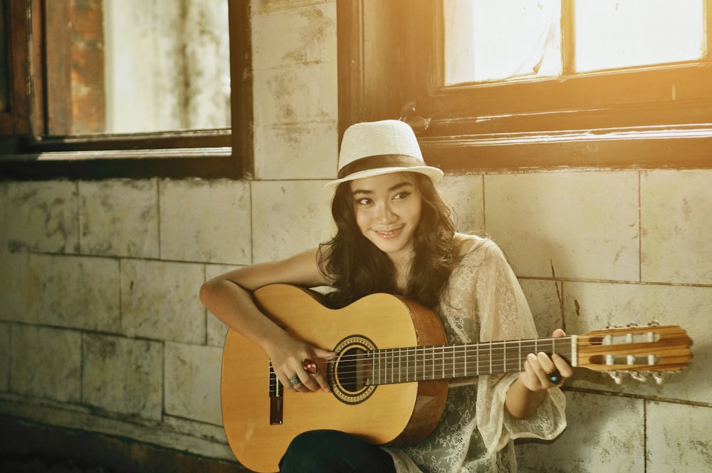 uma mulher com um chapéu está segurando uma guitarra