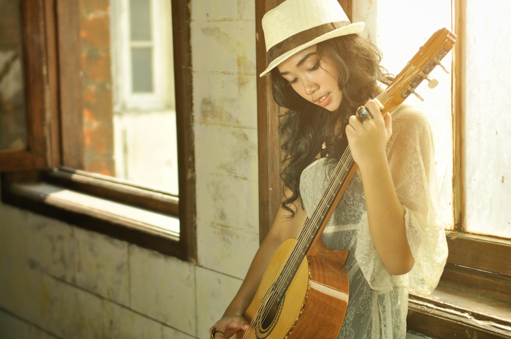 a woman with a hat holding a guitar