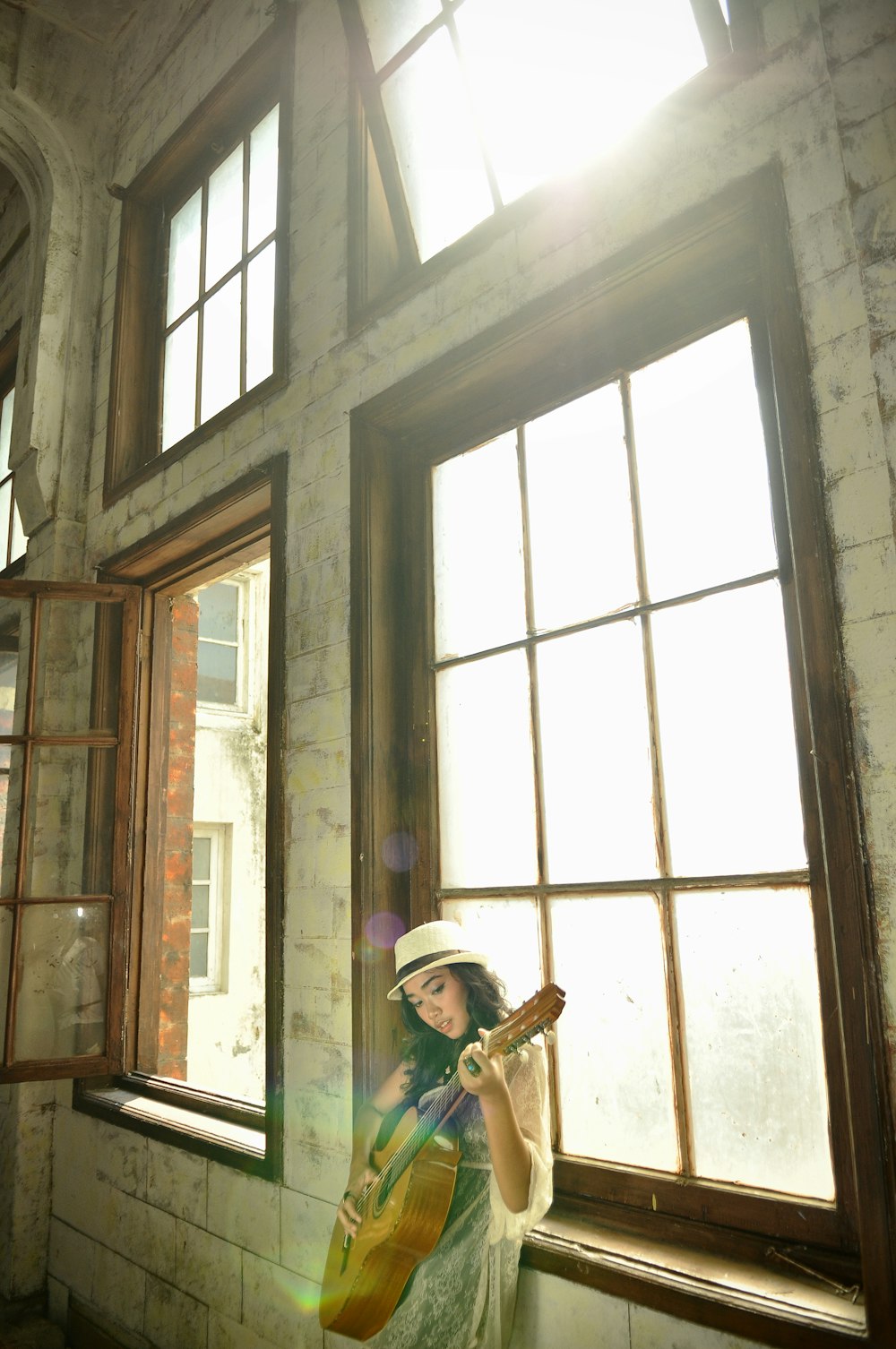 a woman holding a guitar in front of a window