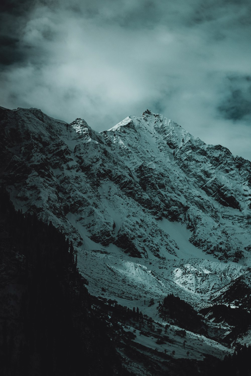 a mountain covered in snow under a cloudy sky