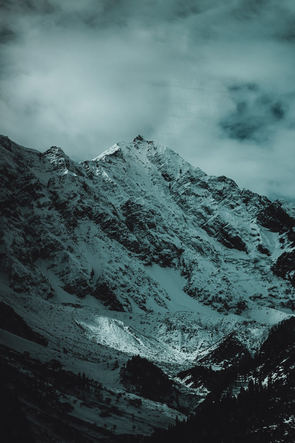 a mountain covered in snow under a cloudy sky