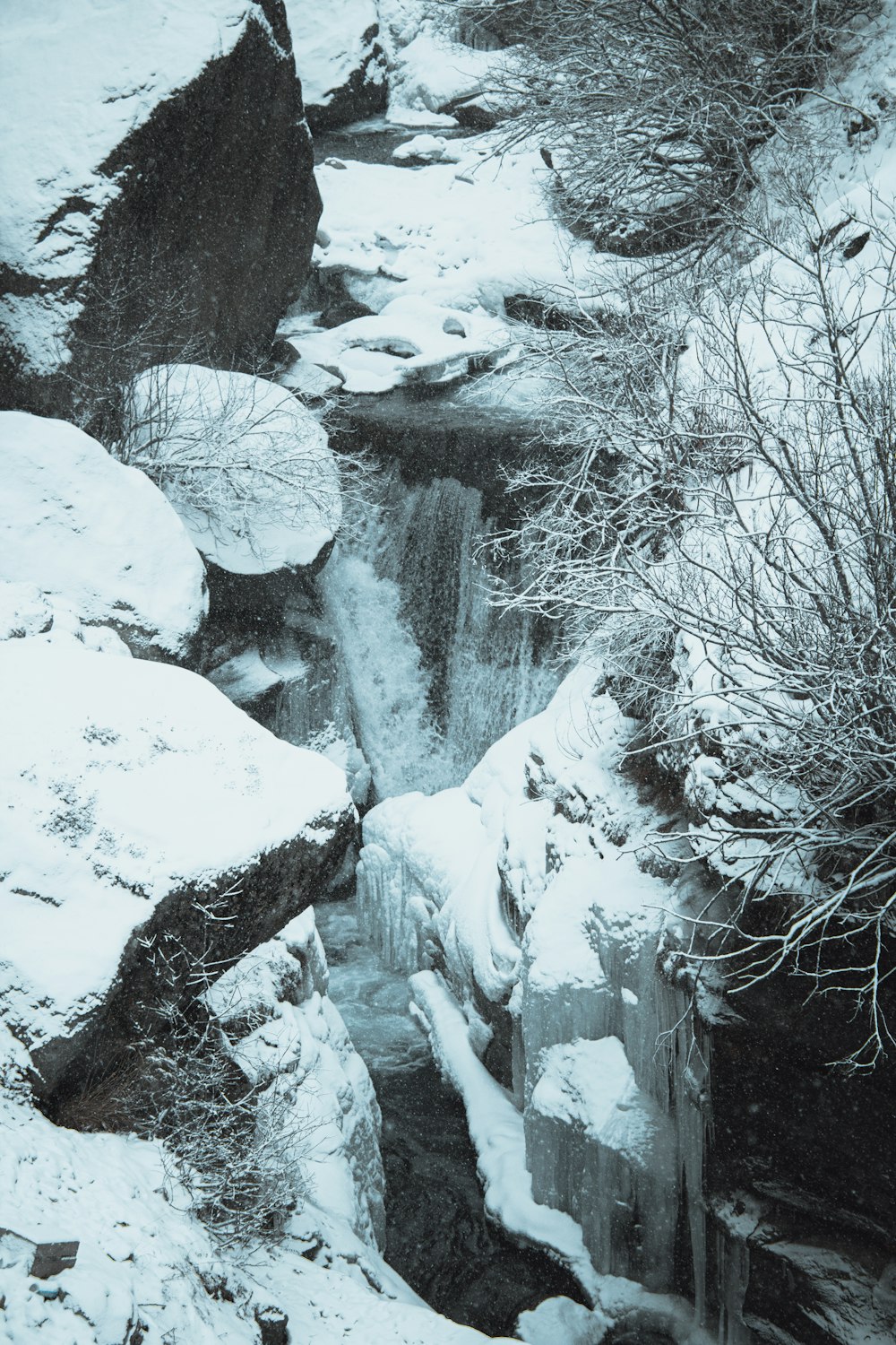 a small waterfall in the middle of a snowy forest