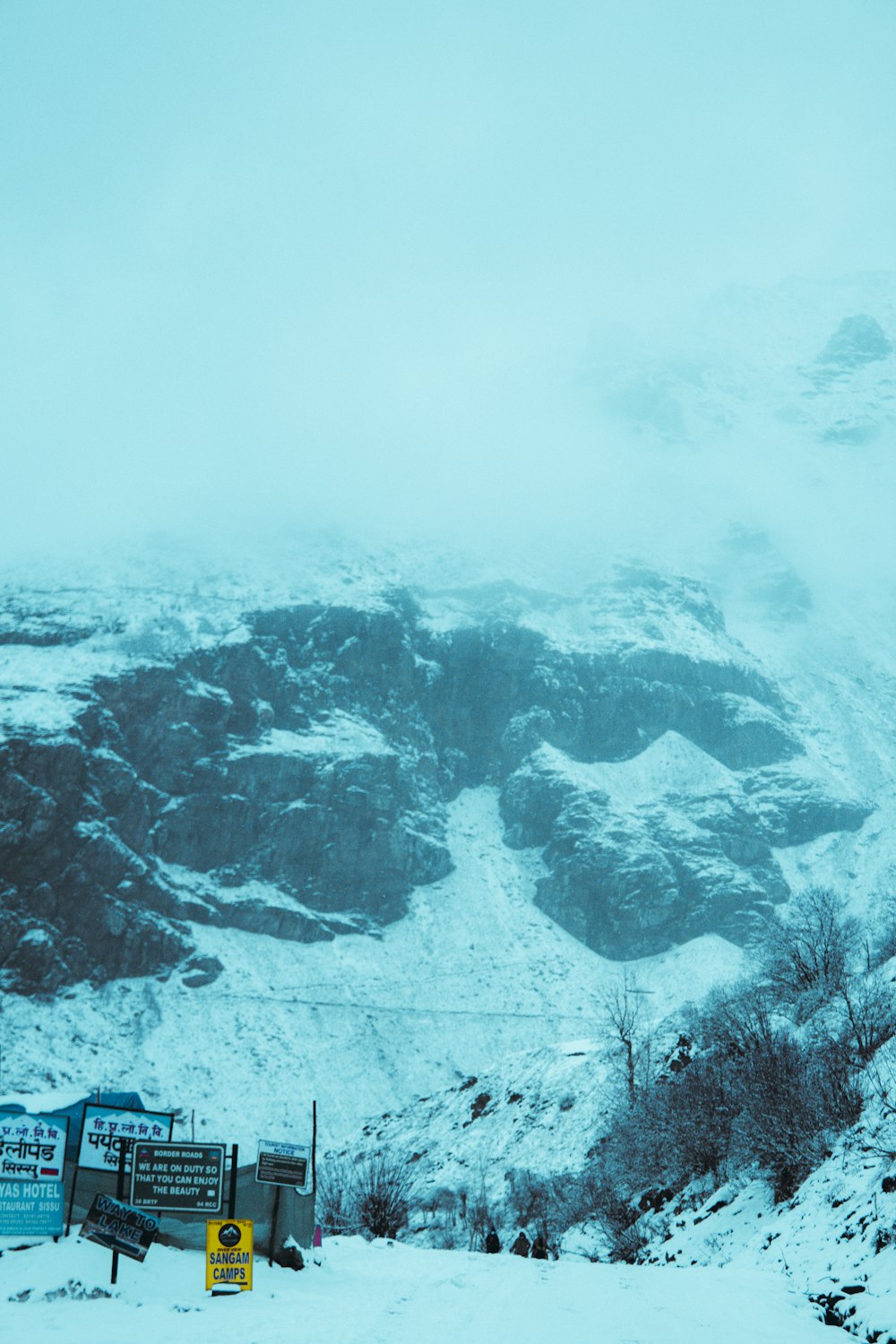 ein schneebedeckter Berg mit einem Schild im Vordergrund
