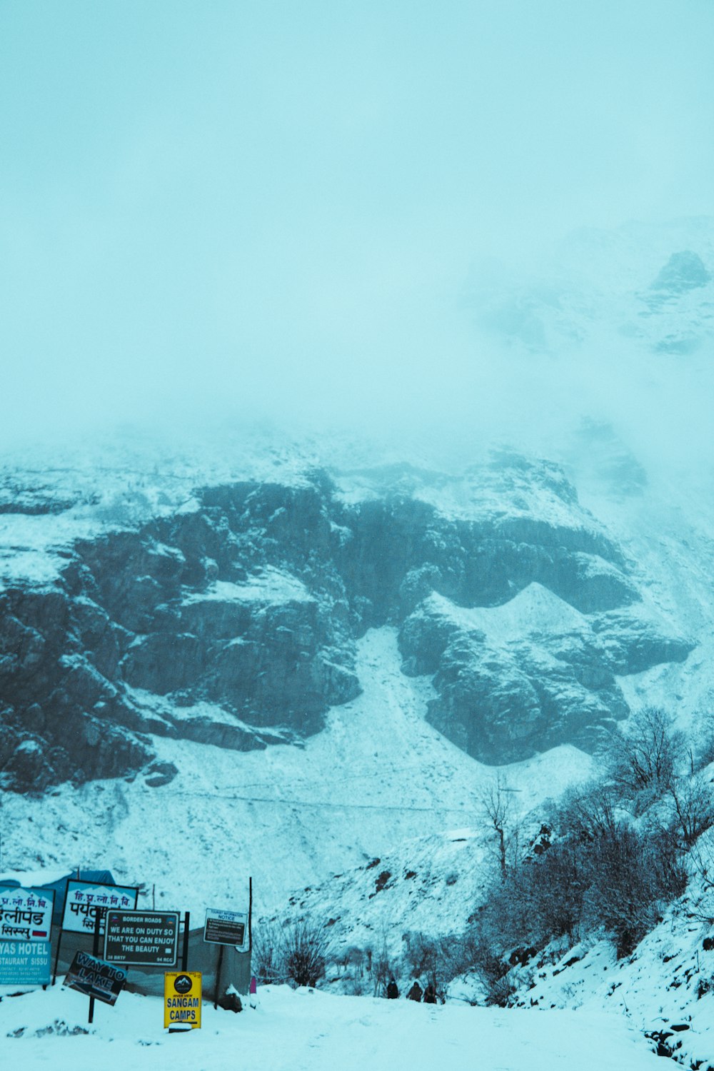 a snow covered mountain with a sign in the foreground