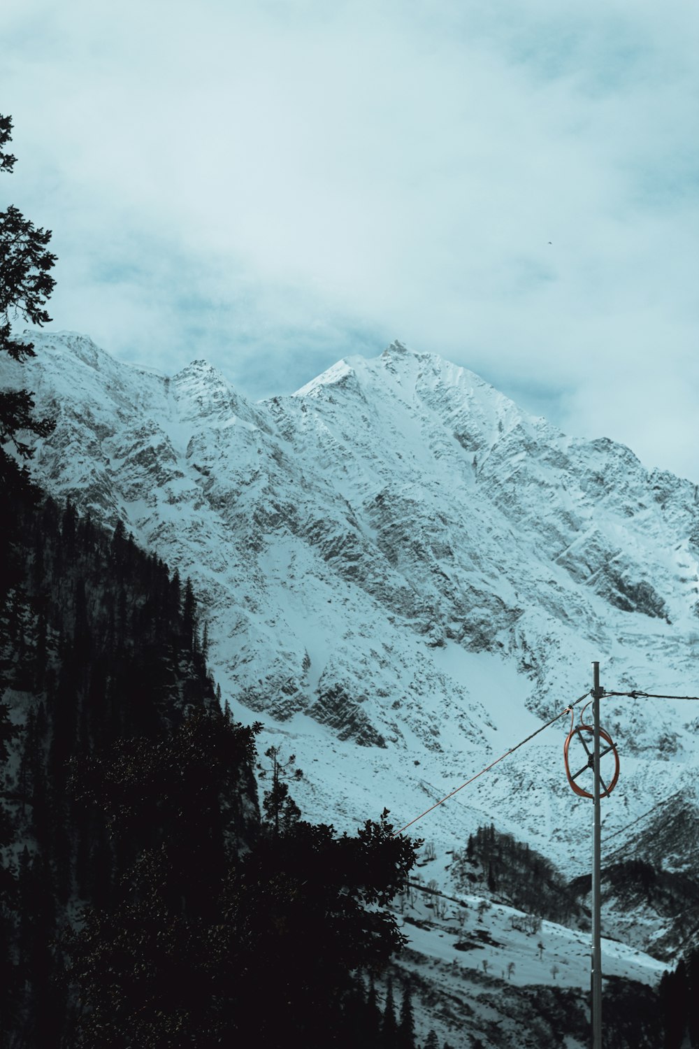 a snow covered mountain with a power line in the foreground