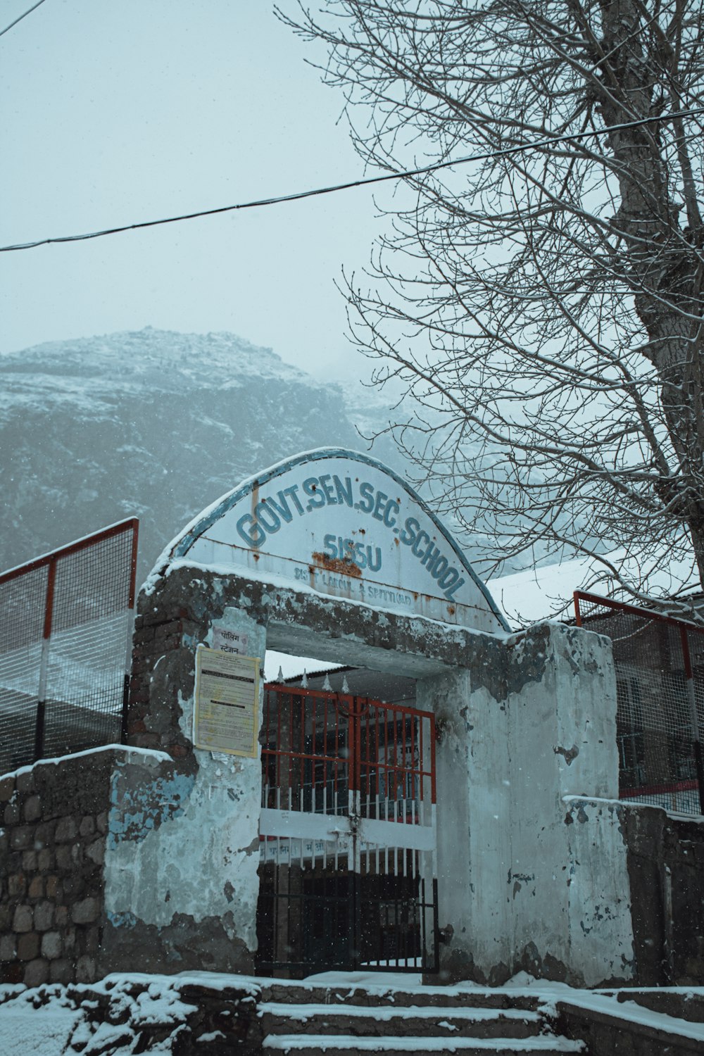 a building with a gate in front of a snowy mountain