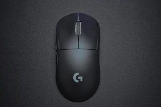 Sleek black gaming mouse with empire gold logo on a distressed dark surface.